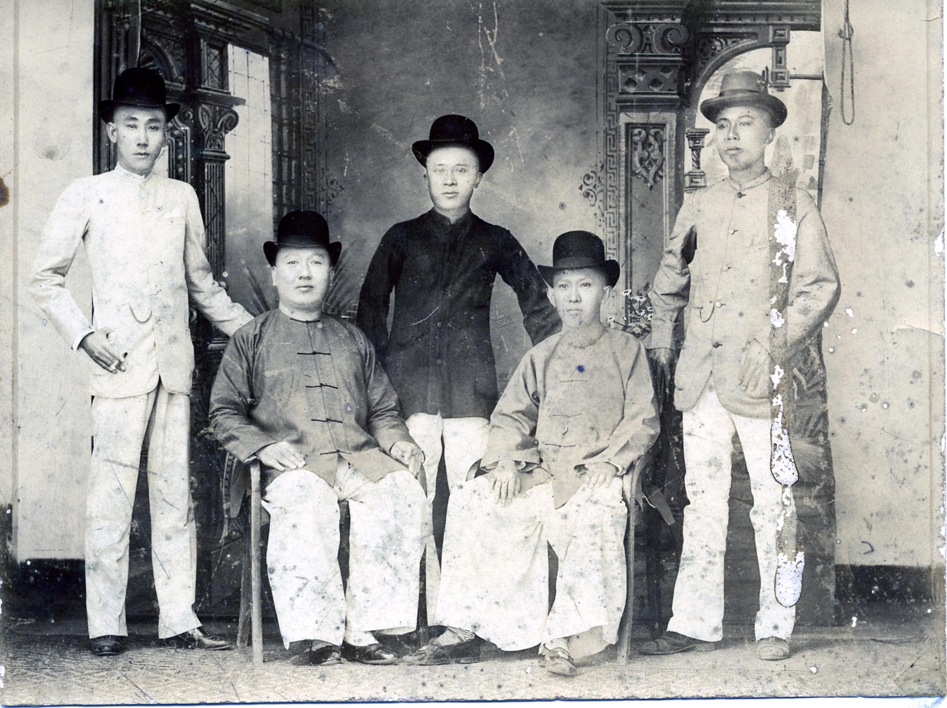 Vintage photo of five Chinese immigrants posing in top hats and traditional shirts