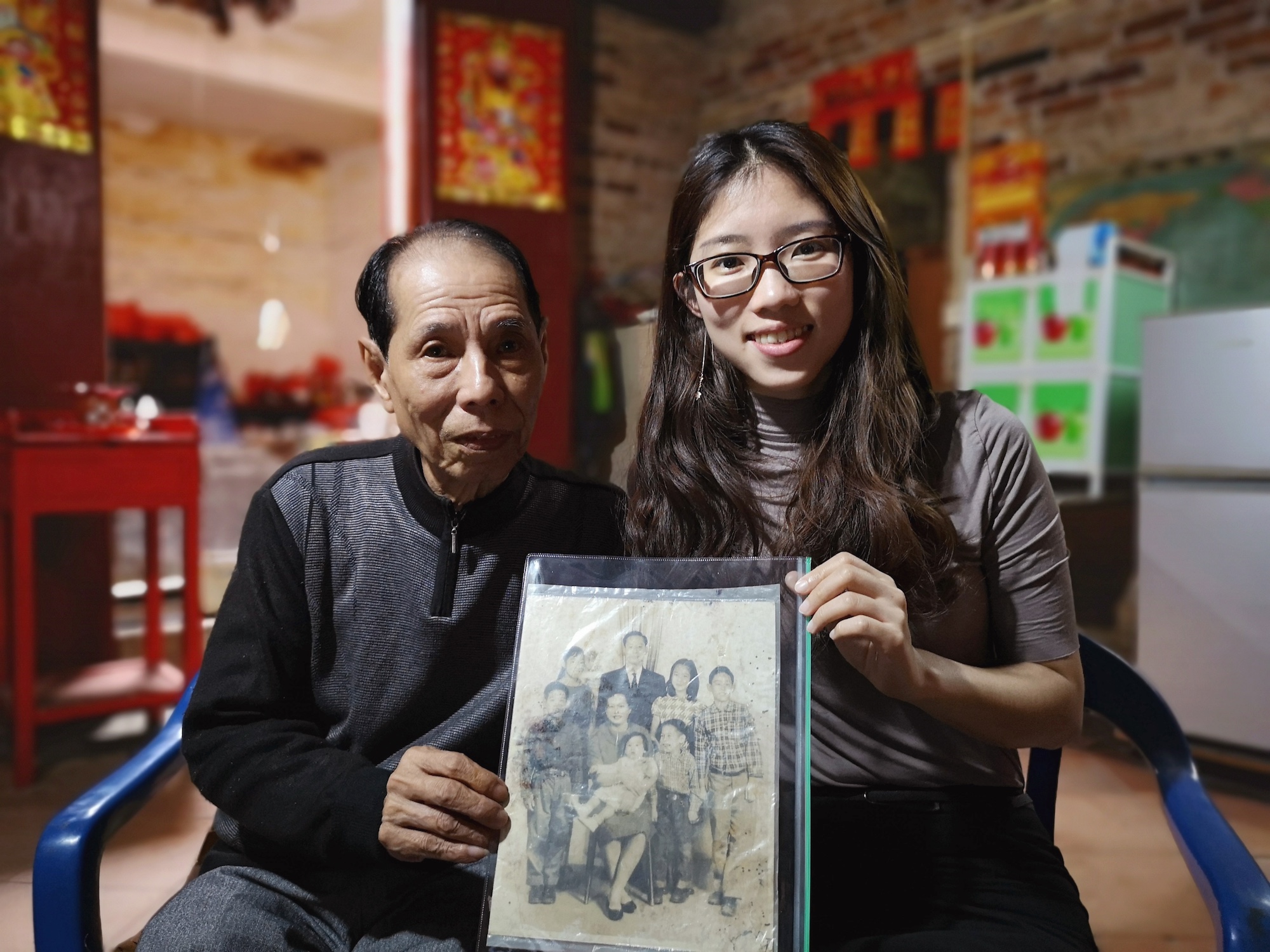 Elderly Chinese relative and My China Roots researcher hold up a vintage family photo