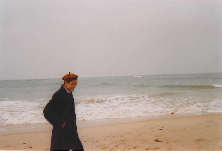 Elderly Chinese man smiling and walking on a beach in Scotland.