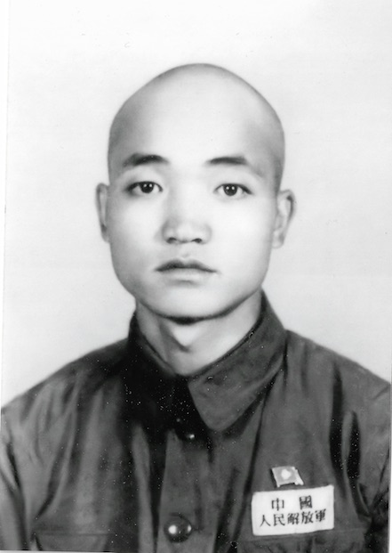 A black and white photo of an 18 year old soldier, wearing a People’s Liberation Army uniform.
