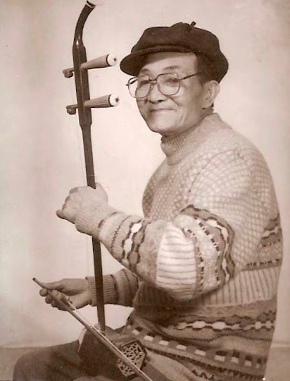 A sepia photograph of Yeye holding his erhu, smiling at the camera