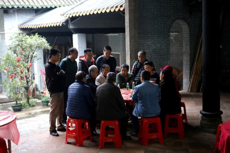 Ying in a group of local Chinese villagers with Ben and Jenny around a red table, translating so they could communicate
