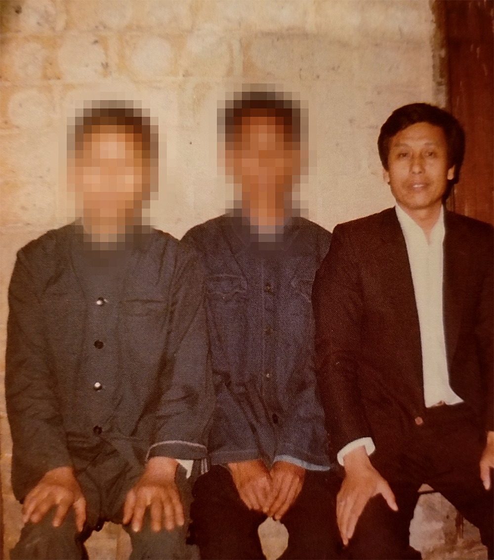 Three Chinese men sitting together. Two wear work uniforms, while the third wears a suit.