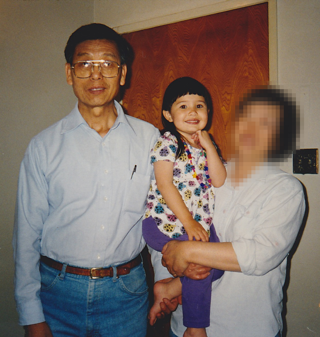 Smiling Chinese grandparents hold their young granddaughter in their arms