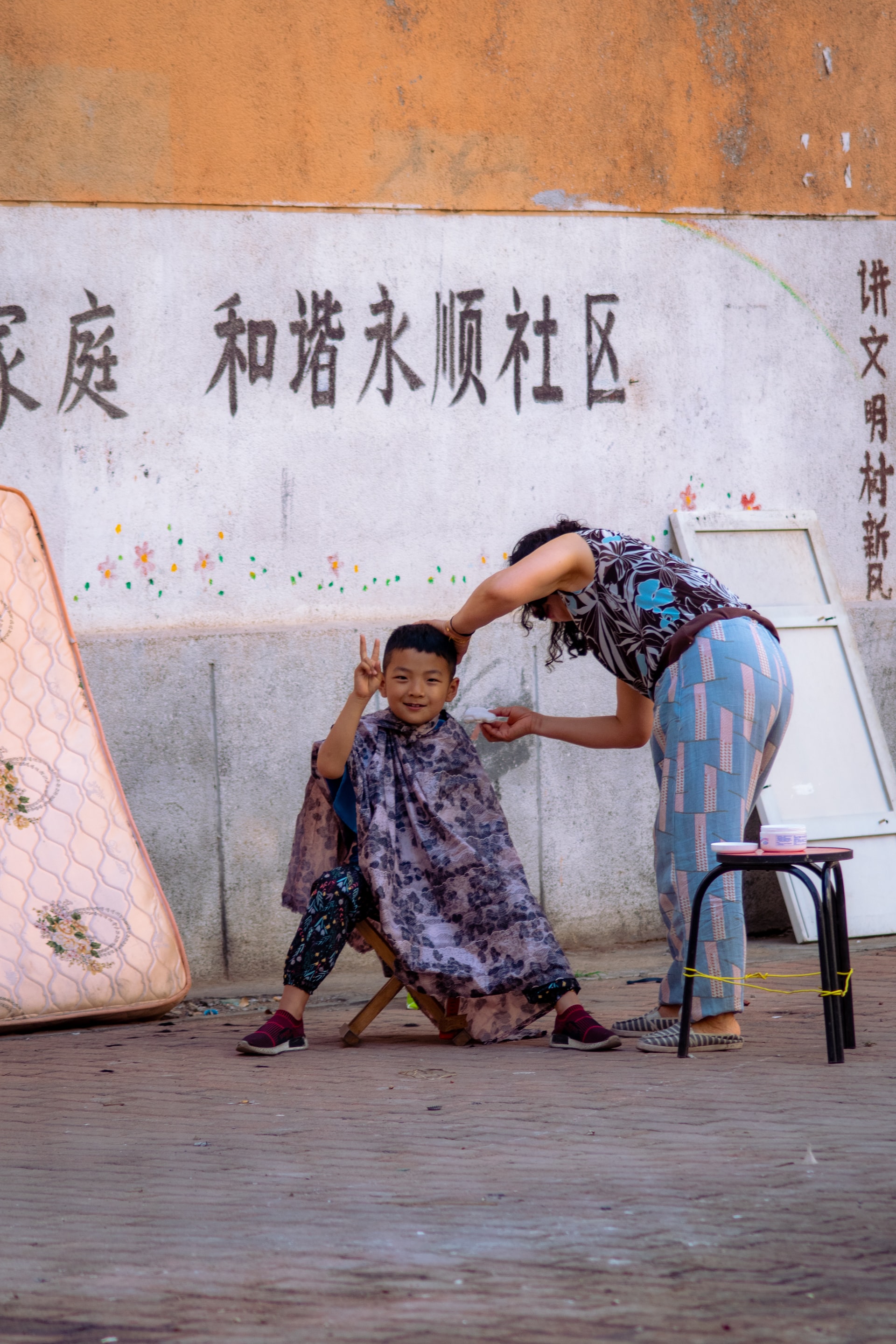 A little Chinese boy getting his haircut on the street.
