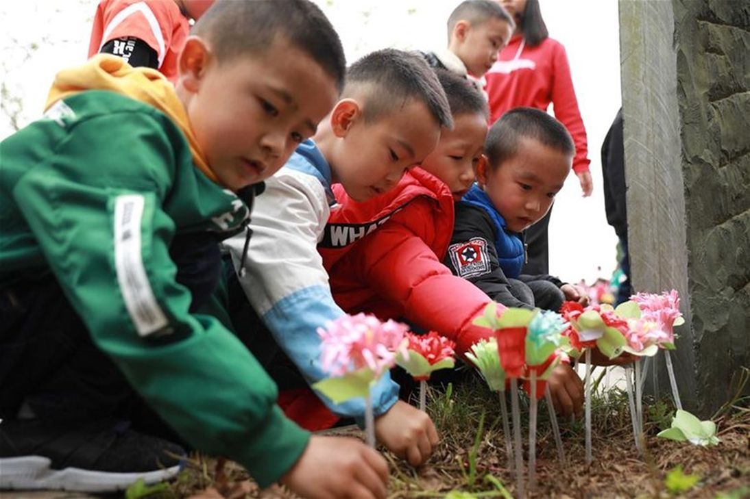 A group of children placing flowers at the side of the gravestone during Tomb-Sweeping Festival.